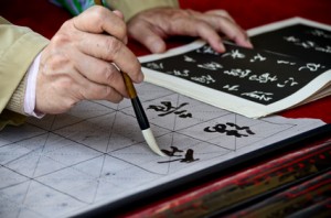 The hands of an elder person writing Chinese calligraphy